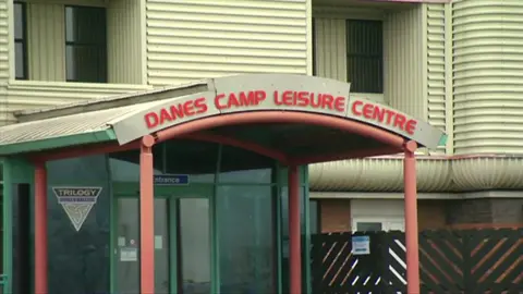 A sign saying Danes Camp Leisure Centre on a awning above the entrance to a leisure centre