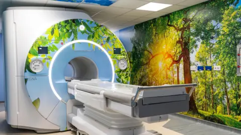 Addenbrooke’s Charitable Trust/Media Studio A scanner covered in images of nature, including a wall with a picture of trees and a large tree trunk