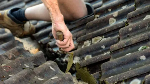 Getty The hands and feet of a roofer seen as they work on a tiled roof