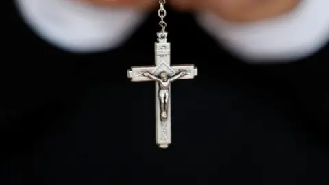 Catholic cross on a chain, with black sleeves in background