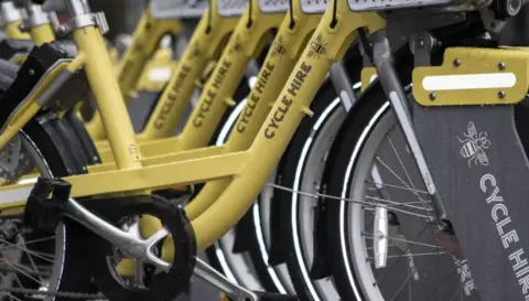 Transport for Greater Manchester Row of Bee Network yellow e-bikes available for hire.