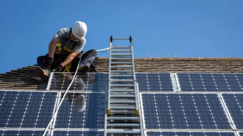 A man installing solar panels on a roof