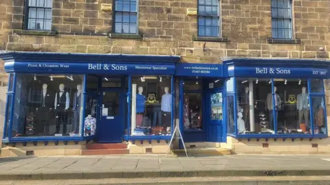 Steve Whiting The front of Bell and Sons, a large shop with a blue front in a Georgian building. 