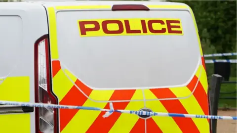 Blue and white police tape and branded police van with red and yellow pattern.