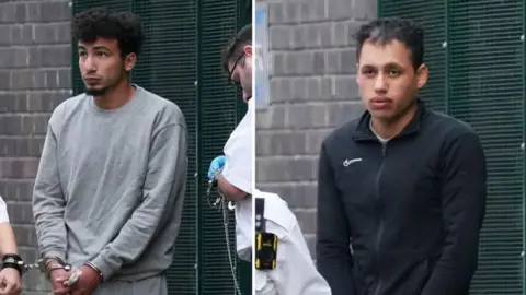 Two men in handcuffs being led from a green metal gate