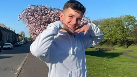Cole Cooper wearing a light-coloured hoodie smiling straight at the camera.