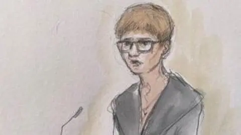 Helen Tipper A court sketch depicting a woman in a grey suit jacket with wide lapels. she has short glasses and dark hair and is speaking into a microphone.