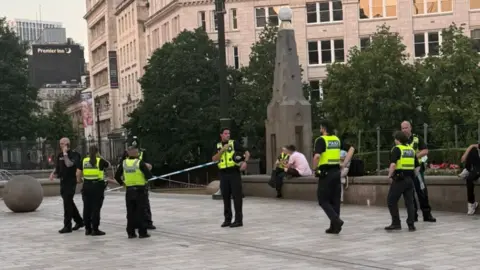Phil Oldershaw At least seven police officers in uniform are standing up. Another police officer in uniform and others are sitting in the background.