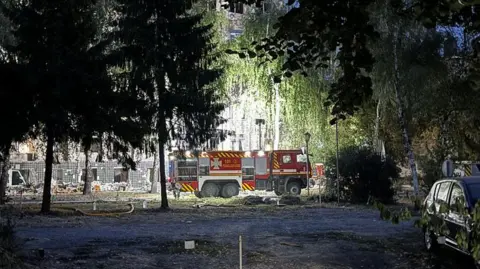 A fire engine is seen through some trees