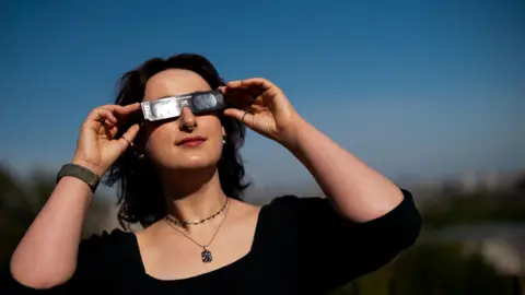 A woman demonstrates wearing Celestron solar eclipse glasses