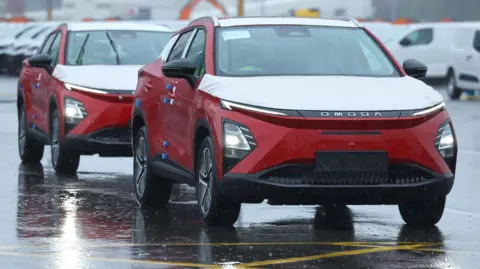 Two red Omoda E5 electric cars manufactured by Chinese automaker Chery are unloaded from a cargo ship at the Royal Portbury Dock, near Bristol.