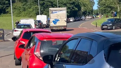A long queue of cars lining a road.