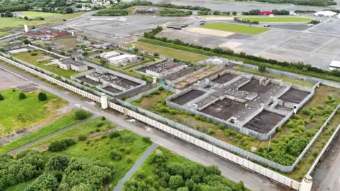 The picture shows an aerial view of the abandoned Maze prison site with the famous H block visible 