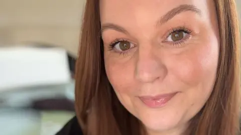 A selfie of Symone, who has brown hair and brown eyes and is smiling at the camera.