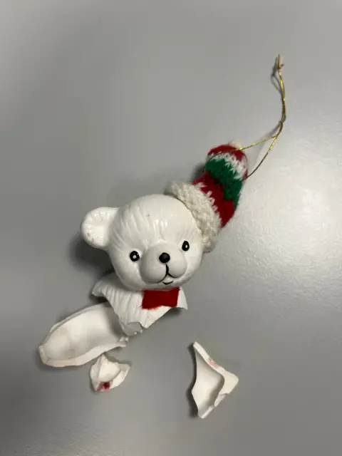 Handout A broken ceramic Christmas tree bauble of a white bear with a woollen hat on. The head and very top of the body are in tact, with a few small pieces also visible.