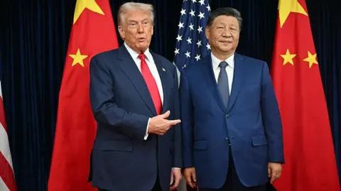 AFP via Getty Images US President Donald Trump (L) and China's President Xi Jinping greet each other as they arrive for talks at the Gimhae Air Base, located next to the Gimhae International Airport in Busan on October 30, 2025