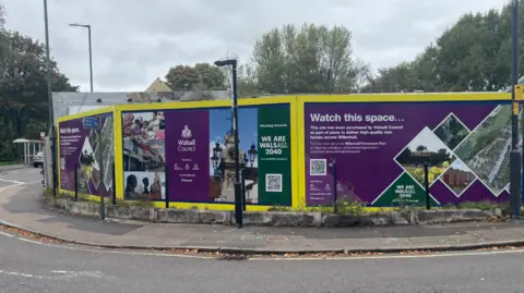 Yellow and purple signage on the corner of a road saying 'Walsall Council', 'We are Walsall 2040' 'Watch this space'