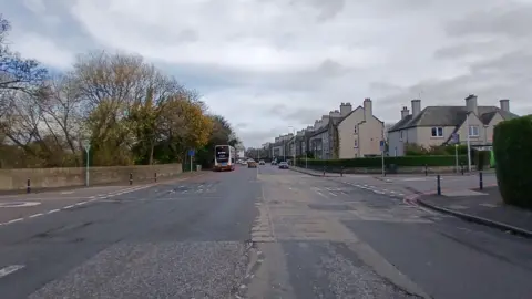Scottish Water A street view of Gorgie Road which is empty apart from a bus in the distance on the left hand side of the road.