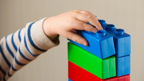 Child's hand playing with colourful building blocks