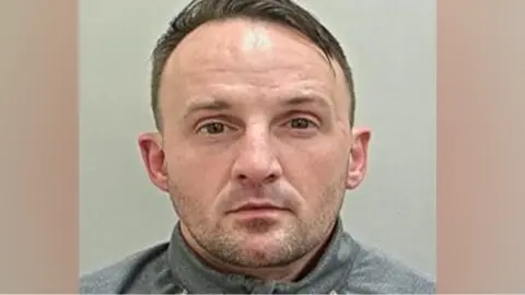 Lancashire Police Micheal Hesketh, with short brown hair and stubble, looks impassively towards the camera in his police mugshot.