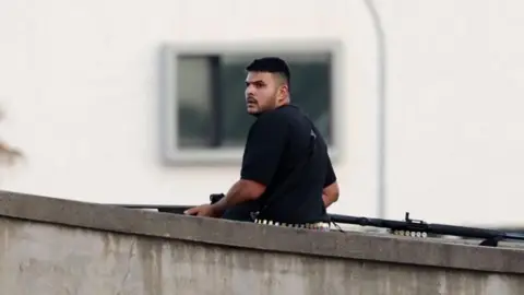 Daily Mail A man wears a black shirt holding a gun