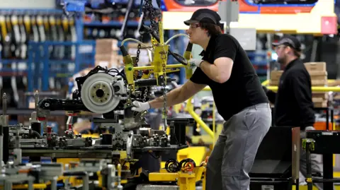 A worker uses a hoist to move components along the production line for the Qashqai model car at the Nissan car factory in Sunderland.
