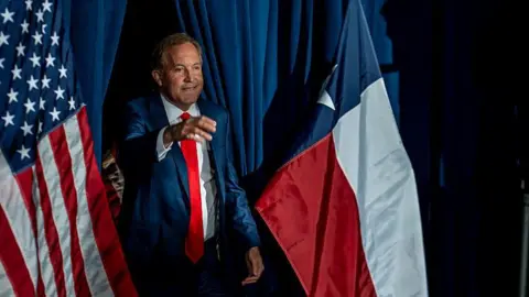 Getty Images Ken Paxton greets supporters in front of an American flag on election night in Texas