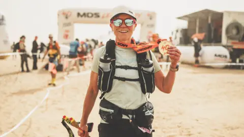 Lesley Malloch Lesley Malloch holding up her medal at the finish line having completed the race.