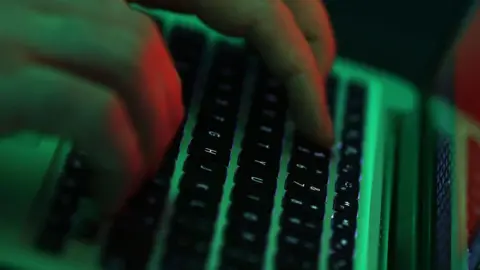 Getty Images A person types on a laptop keyboard illuminted by green light.