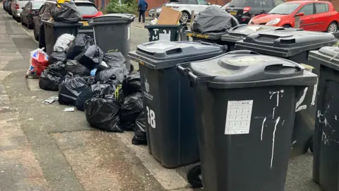 BBC Bins in Warrington with rubbish bags on the floor next to them
