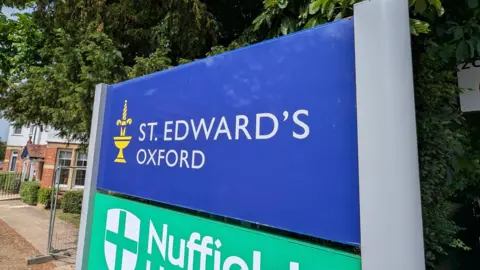 A blue sign with white writing that says 'St Edward's Oxford'.