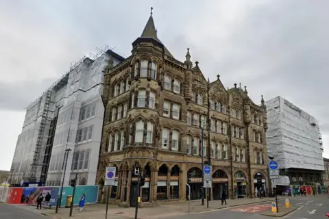 A view of the the Estate Buildings from street level. The building is four-storey's tall and has several spires on its roof.