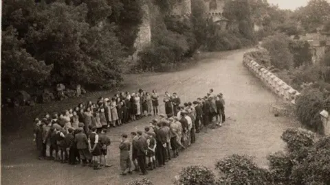 Gwyrch Castle Trust Archive Black and white picture of the children on the castle grounds. The group is in the distance, standing in a rectangle. 