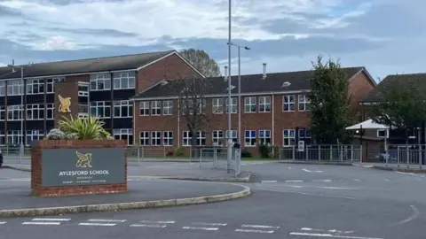 Handout General view of buildings and a wall with the words Aylesford School and a motif of a bird.
