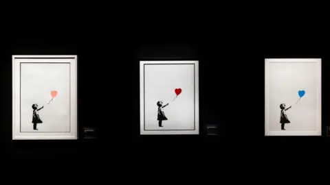 PA Media Three versions of the Girl With Balloon by Banksy, on display at The Art of Banksy exhibition in July 2023