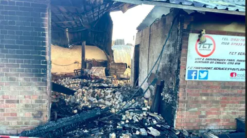 Steve Huntley/BBC A burned out brick built barn, with a warped metal roof and charred masonry and bricks heaped on the ground