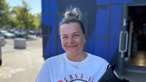 George King/BBC A head and shoulders image of Kirsty Acott. She is wearing a Guns N Roses T-shirt and smiling into the camera.