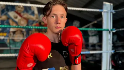 Jerry-Mike wearing red boxing gloves and a black sleeveless T-shirt