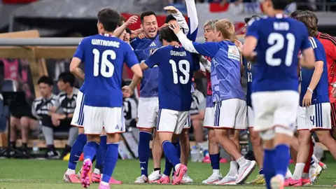 Japan players, in blue, celebrate a goal