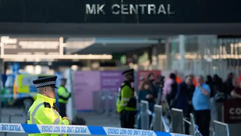 PA Media display the entrance to the Central Milton Keynes station. Police collar as well as officers who stand inside the collar can be seen. The audience can be seen moving out of the collar around the station.