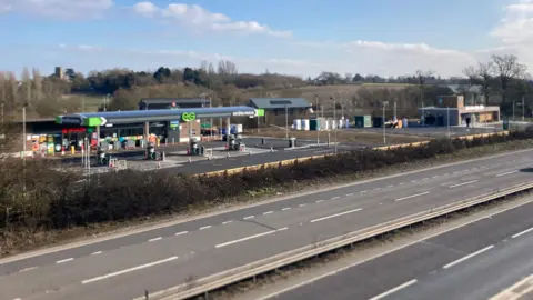 The petrol station and a Starbucks in the background, with the dual carriageway in front of it.