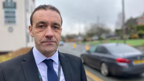 A man in a suit looking dour stood by the road safety scheme