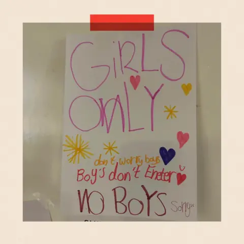 The felt‑tip sign taped to the door of a private room