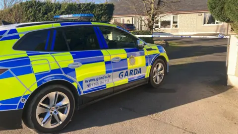 A garda car at the house. A police cordon is up at the gate to the house