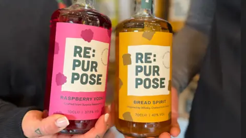 Two glass bottles, one with a pink label and the other a yellow label with the word Repurpose on both