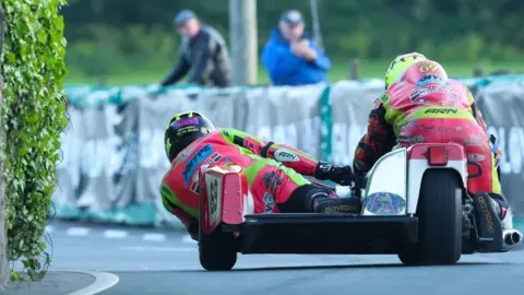 SOUTHERN 100 A red classic sidecar outfit photographed from behind while rounding a bend.