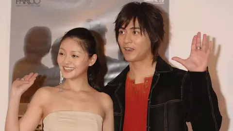 Getty Images Hsu and Vic Chou standing side by side and raising their hands at an event in Tokyo