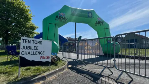 A sign with the words 'TEN TORS CHALLENGE FINISH' on the left, and a large inflatable archway which has the words 'ARMY' on it.