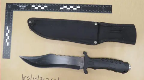 British Transport Police A knife with a sheath next to it. The knife has a curved blade with a sharp point.