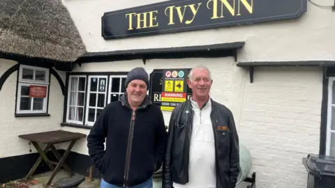 Dr Paul Moyle-Harris standing in front of The Ivy Inn pub